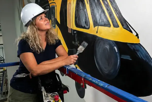 Artist painting large yellow helicopter mural