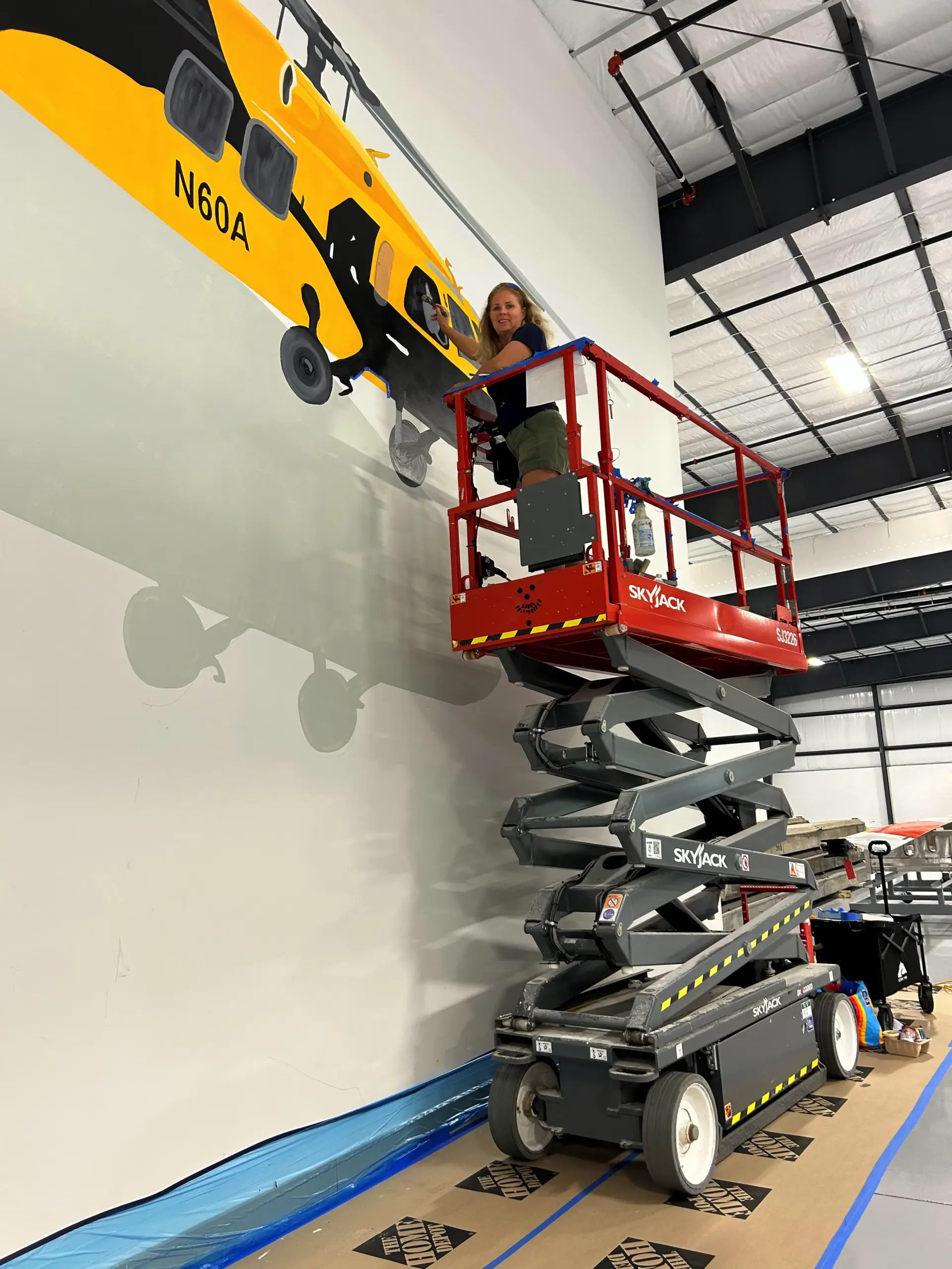Artist painting large helicopter mural indoors