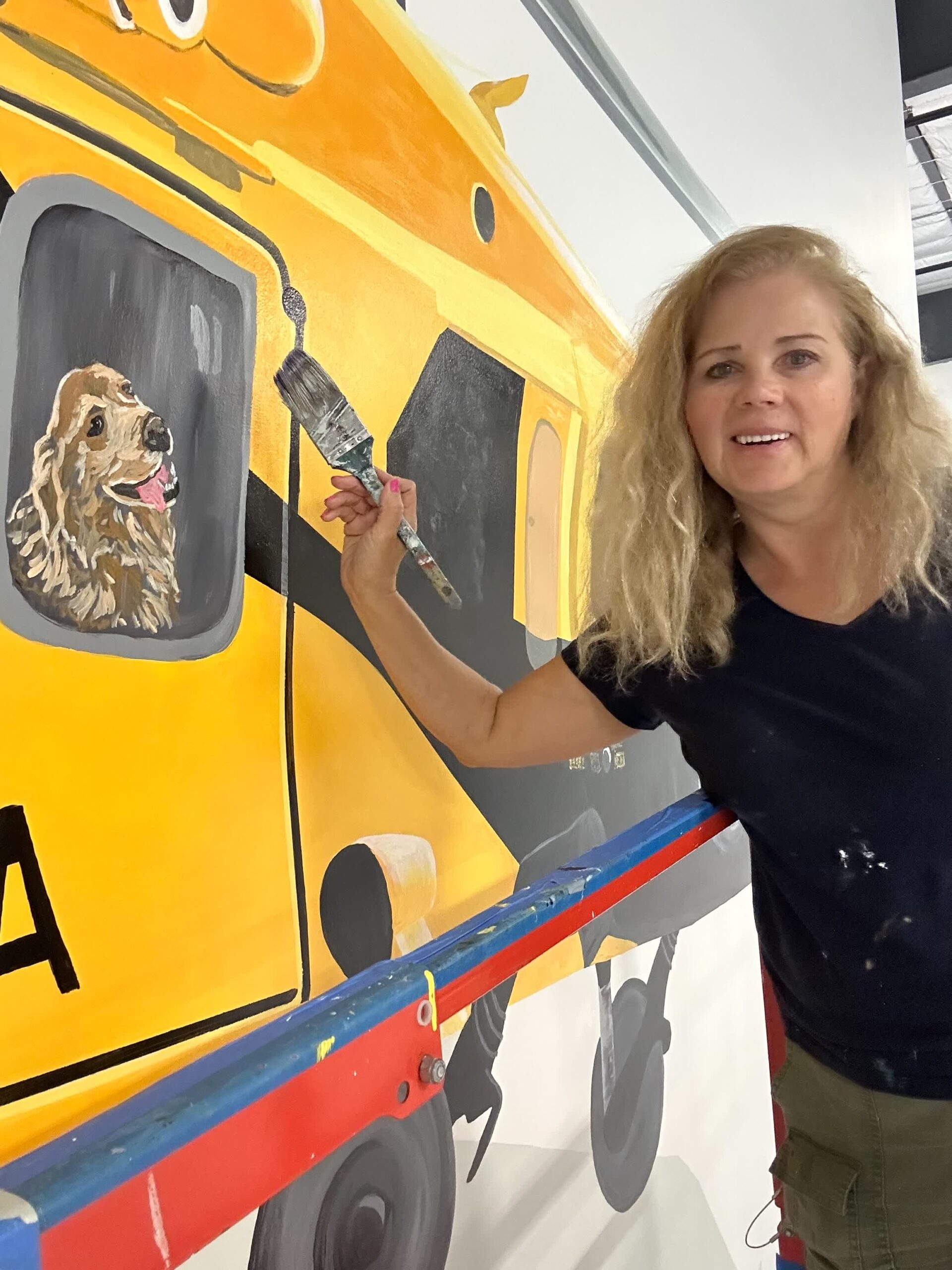 Artist painting dog on yellow vehicle mural