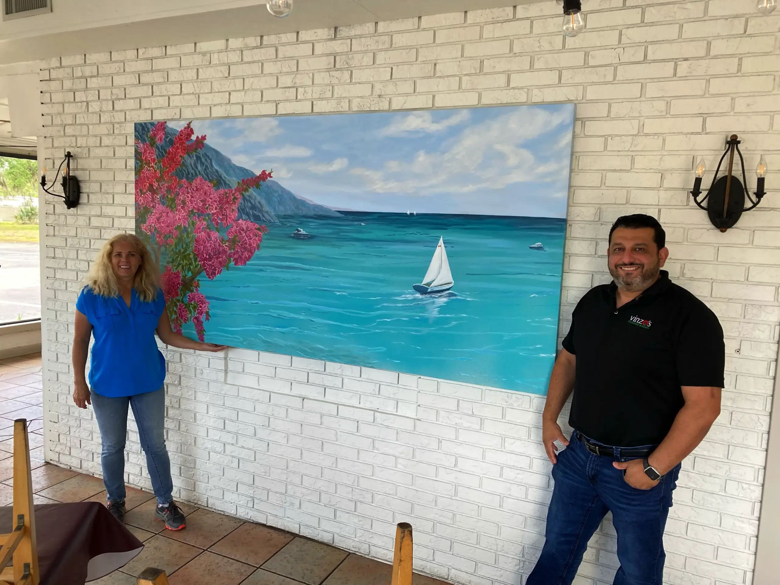 Two people standing beside ocean painting