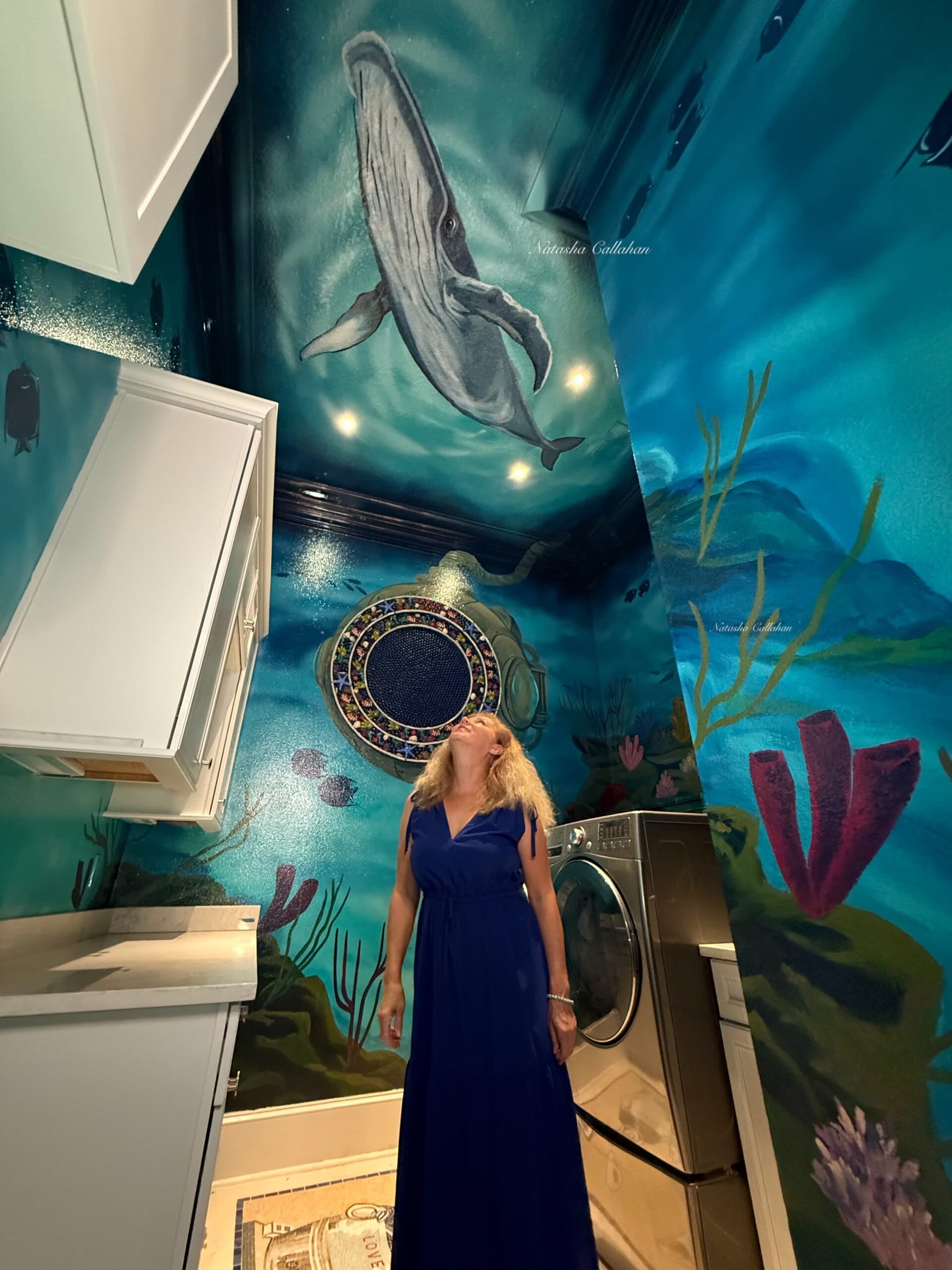 Woman in ocean-themed laundry room with whale mural