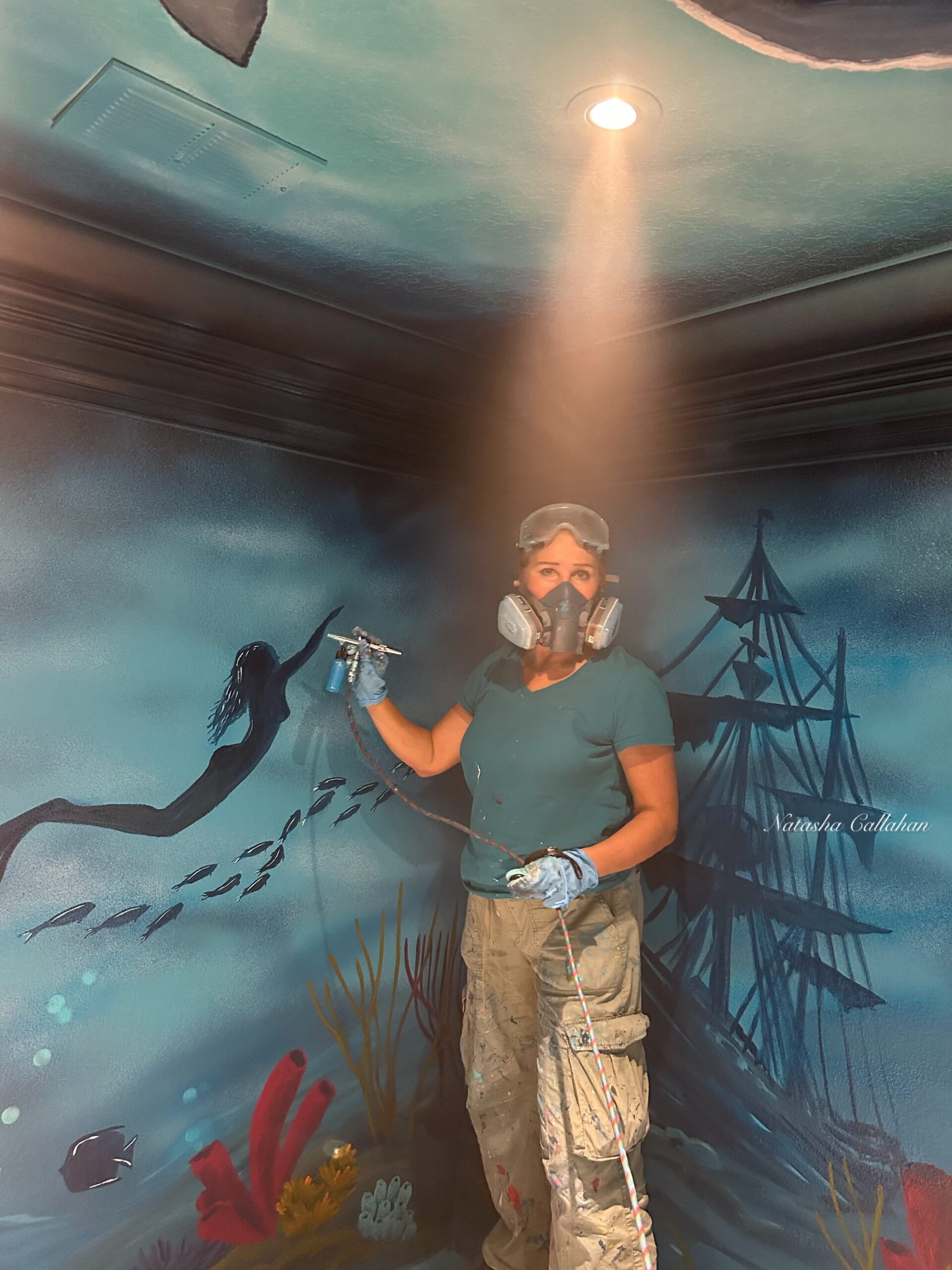 Artist painting ocean mural with airbrush