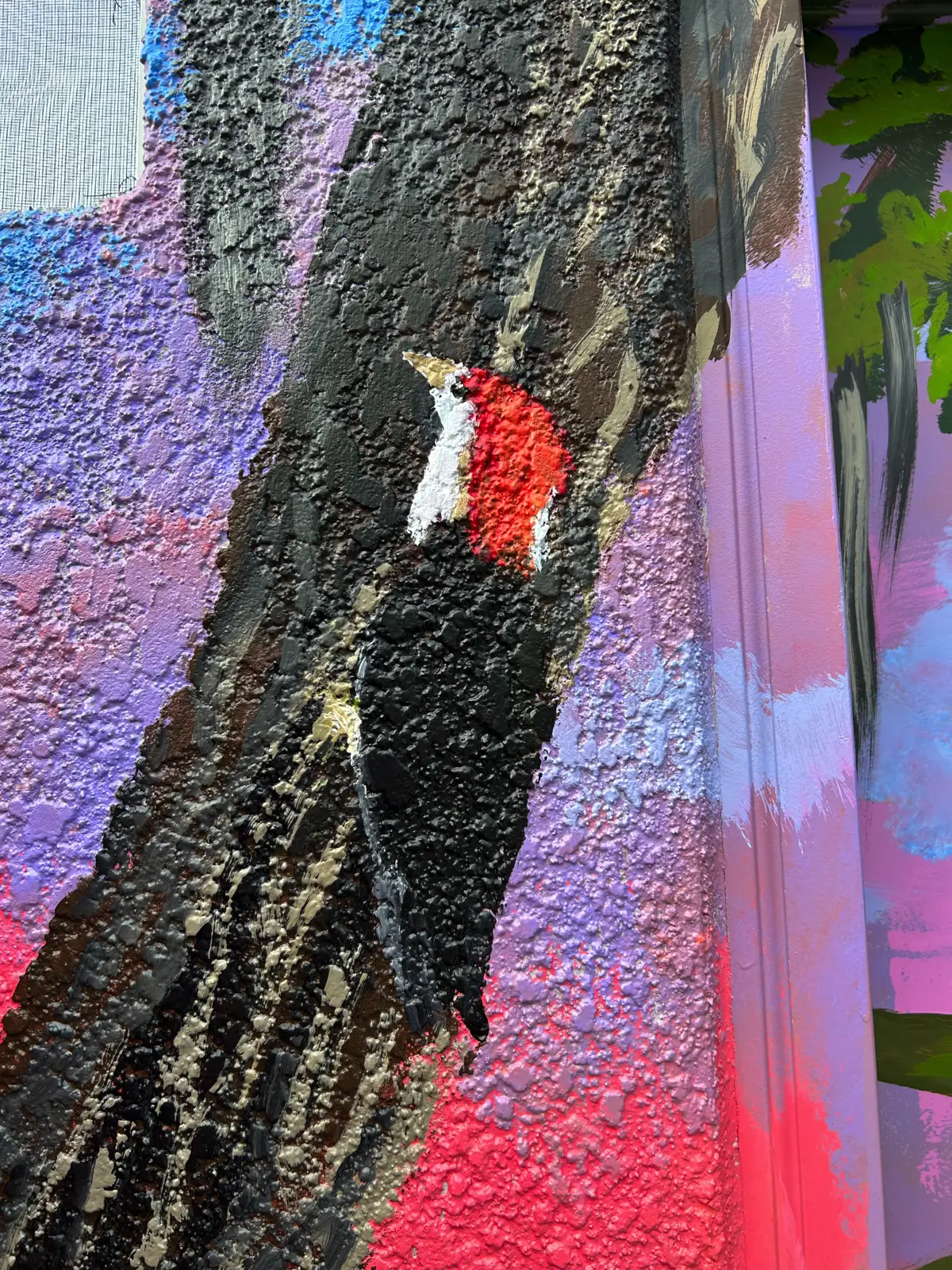 Colorful mural of woodpecker on textured wall