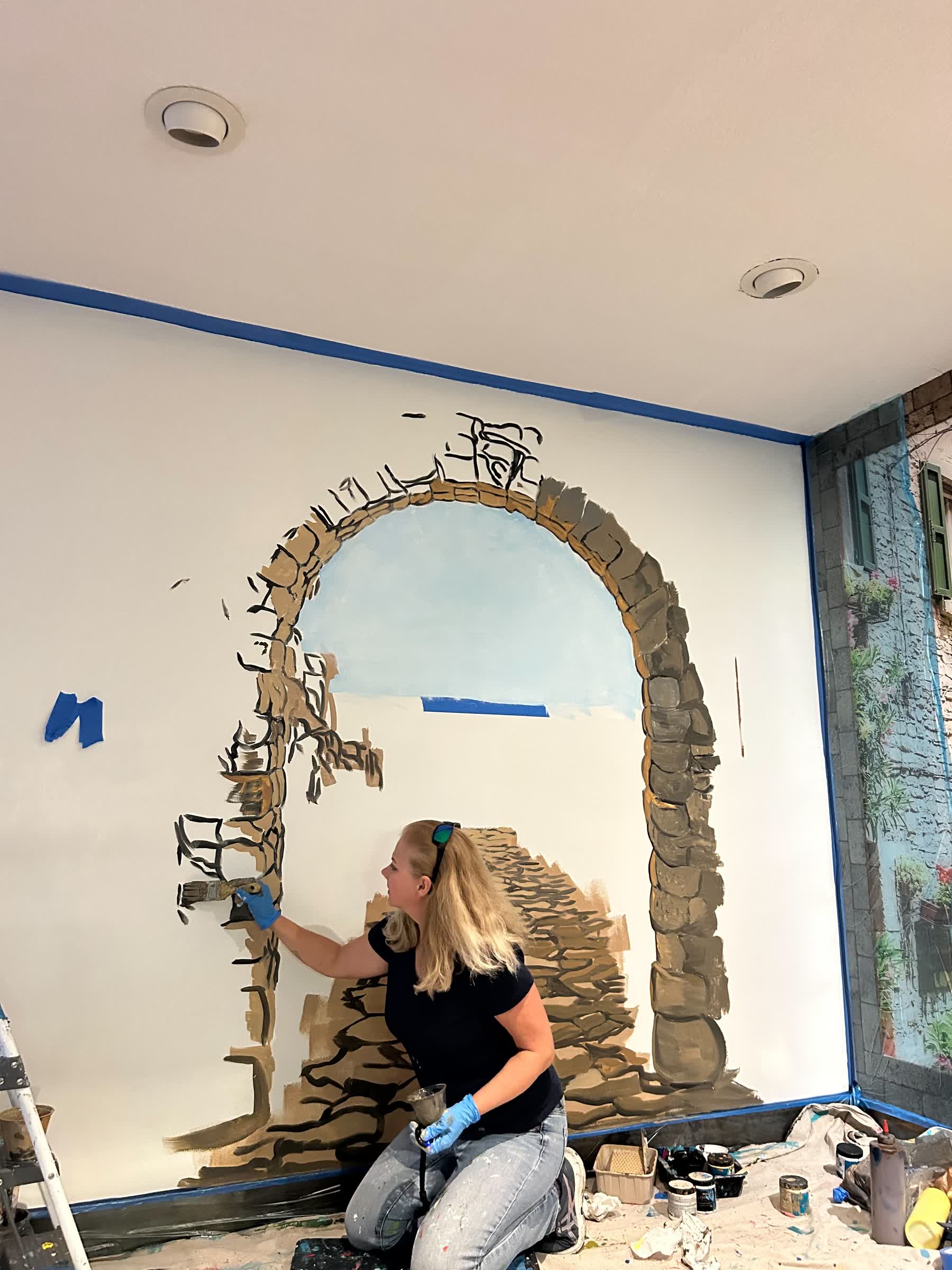 Artist painting stone archway mural indoors