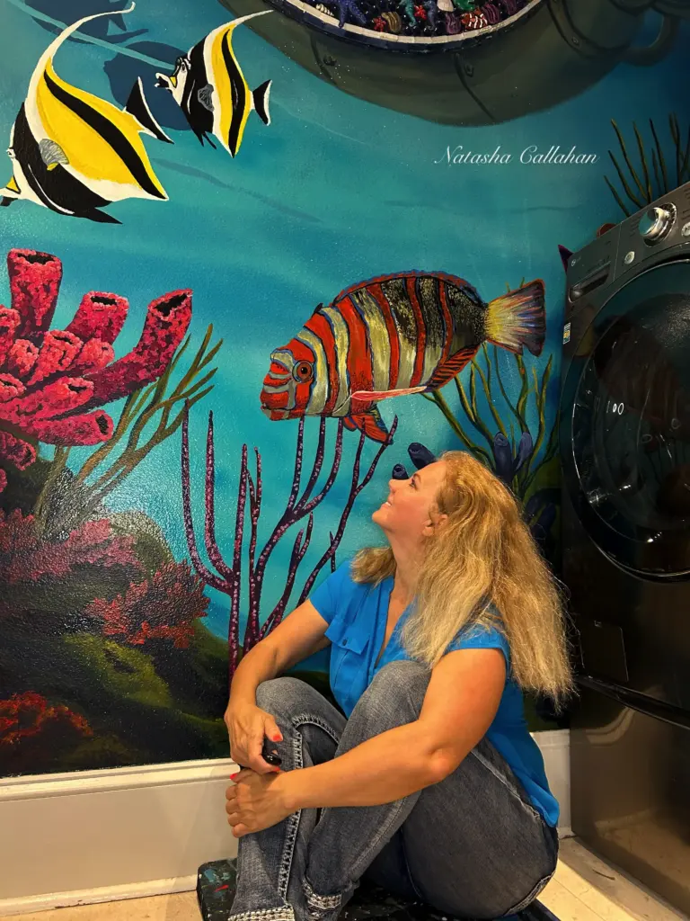 Woman sitting by colorful underwater mural.