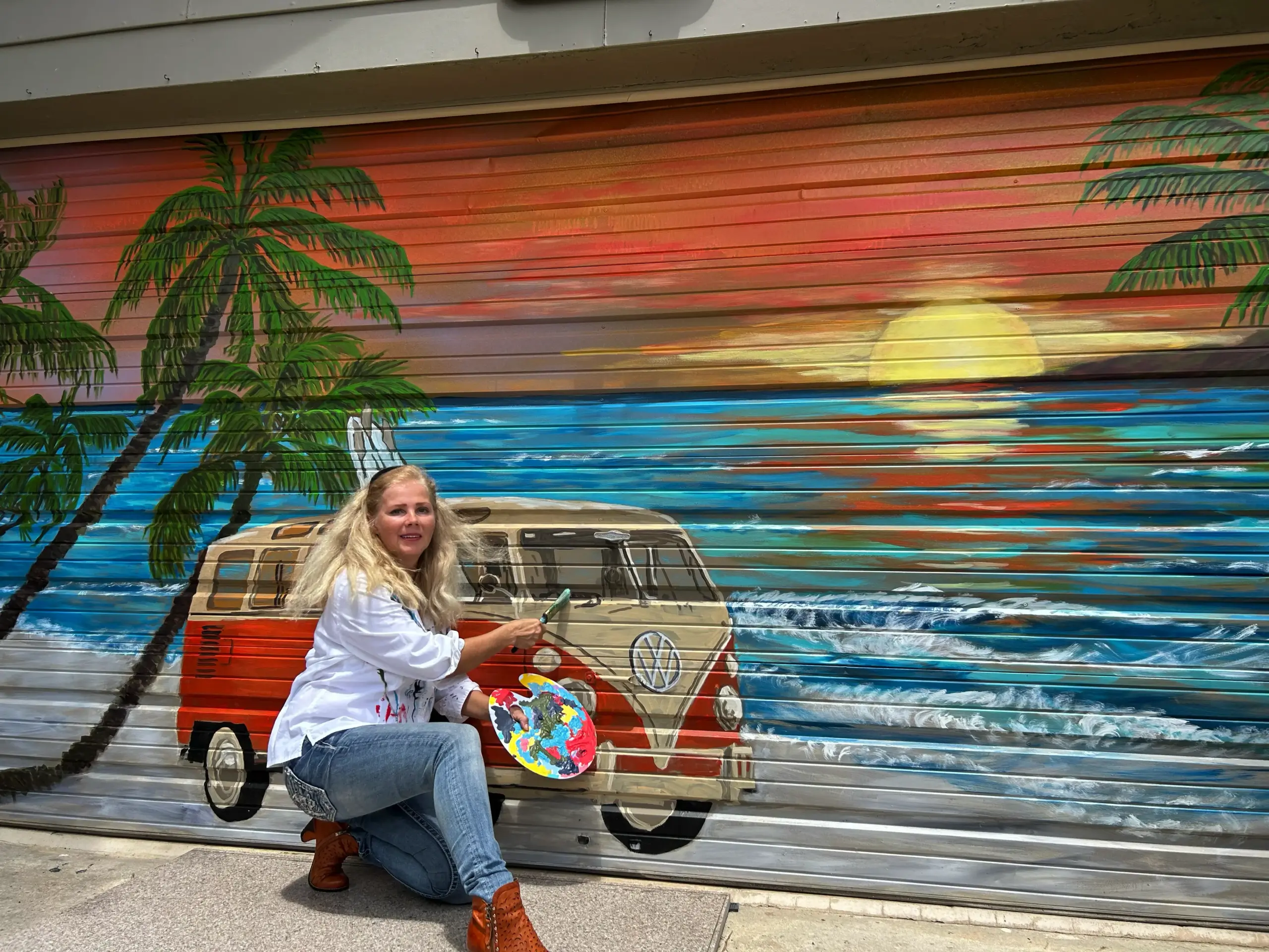 Artist painting beach sunset mural on garage door