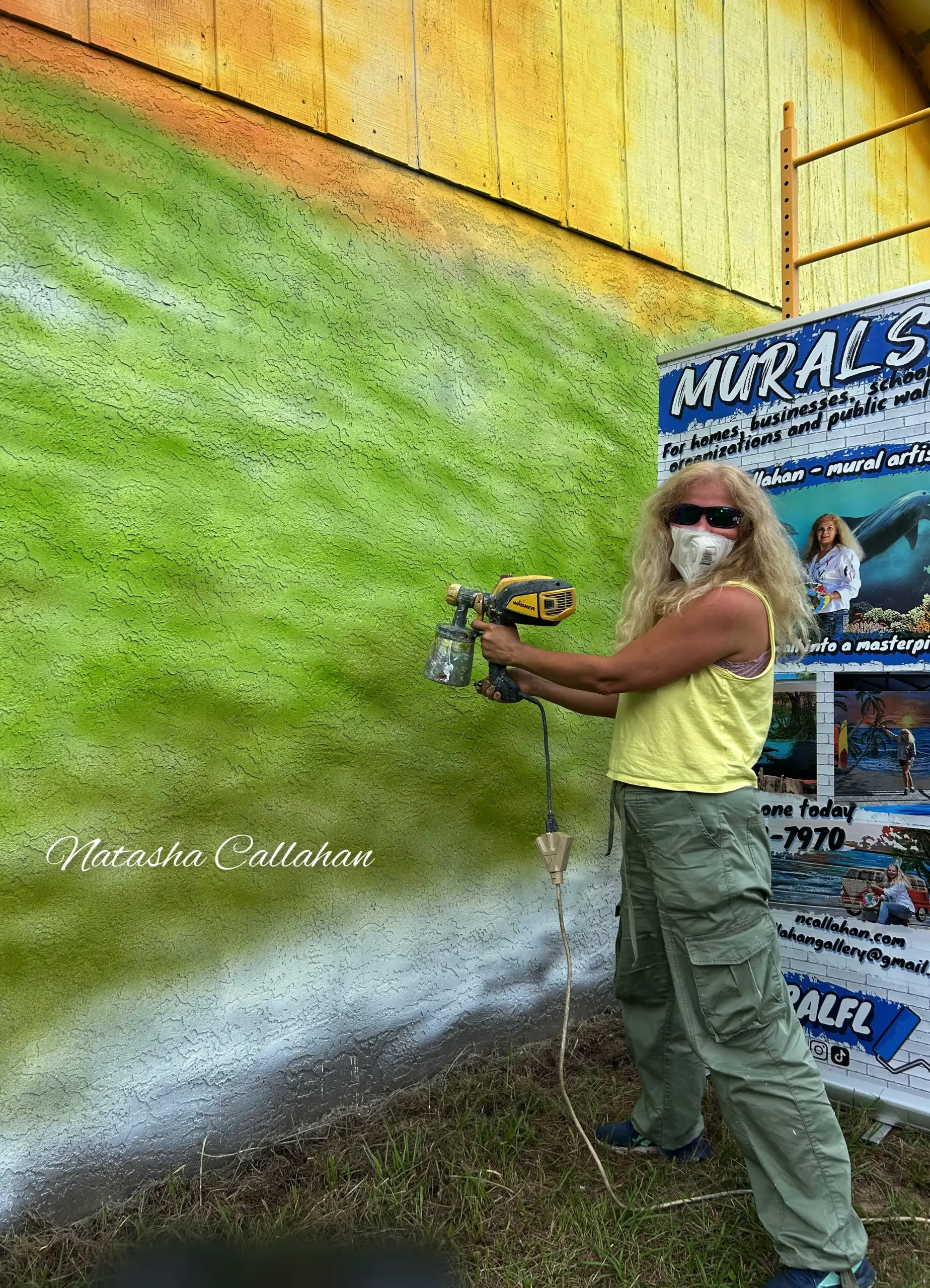 Artist spray painting green mural wall